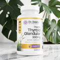 Dr. Dale Wellness Retail Thyroid Glandular Support Complex 300mg supplement bottle on a marble surface with green leaves.